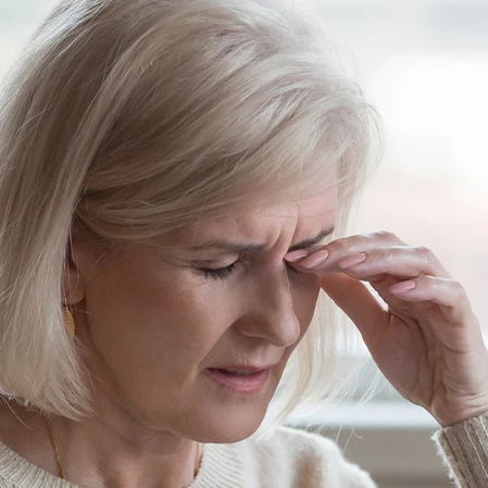 A woman rubbing at her eye in irritation from a dry eye condition